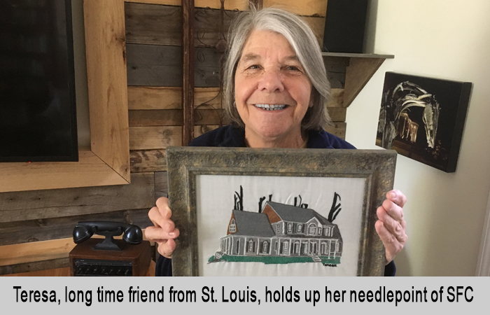 Teresa, long time friend from St. Louis, holds up here needlepoint of St Francis Cottage